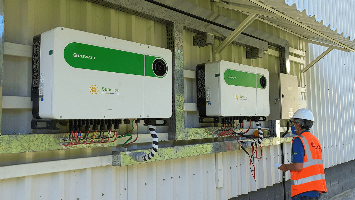 dois inversores de energia fotovoltaica sendo instalado por um engenheiro